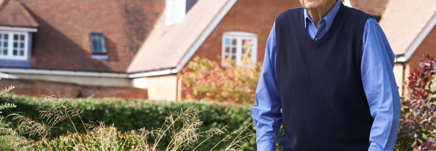 Older man using a walking assistance device on a sidewalk
