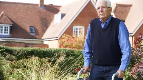 Older man using a walking assistance device on a sidewalk